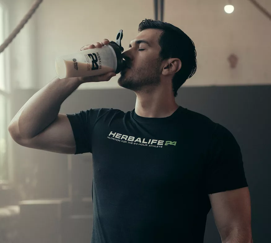 A man drinking a Herbalife24 recovery shake after training